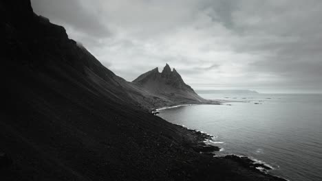 Montaña-épica-Aérea-De-Vesturhorn,-Playa-De-Arena-Negra-Stokksnes,-Paisaje-Volcánico-Oscuro-Y-Nublado,-Islandia