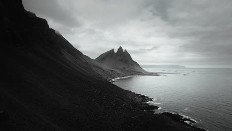 Luftepisches-Vesturhorn-Gebirge,-Schwarzer-Sandstrand-Stokksnes,-Vulkanische,-Dunkle,-Stimmungsvolle,-Wolkige-Landschaft,-Island