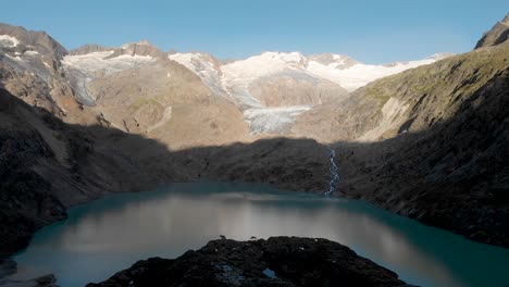 Aerial-view-of-the-glacial-lake-of-Gauli-glacier-in-the-Bernese-Oberland-region-of-the-Swiss-Alps-as-first-light-illuminates-the-mountains-peaks-after-sunrise