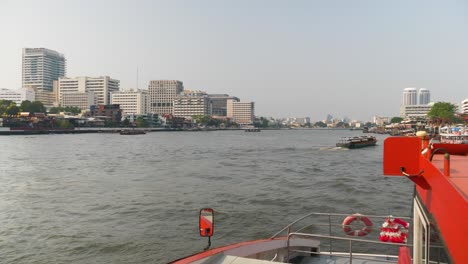 view of the chao phraya river from a ferry boat with bangkok skyline in the distance