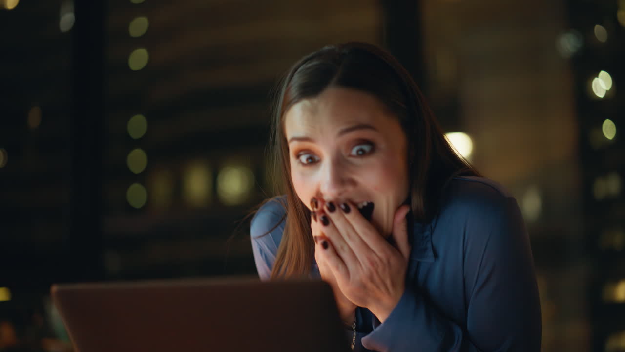 Woman entrepreneur rejoicing success at laptop in dark office working closeup