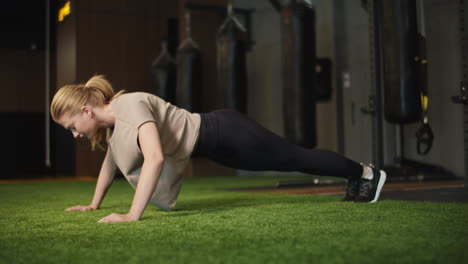 Active-female-boxer-doing-pushups-in-sport-club.-Fit-girl-warming-up-at-gym