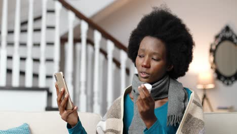 close up portrait of sick woman wearing a scarf, sitting and videochatting on cellphone