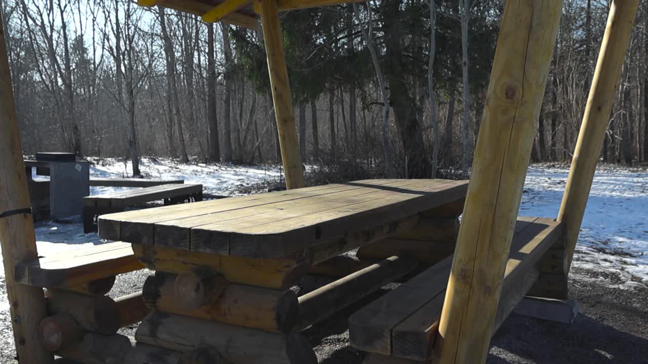 Panning over camping site with fire place in the woods at Tabasalu Nature Park Estonia. Ideal for winter retreat and connecting with nature. Rustic recreation site. Hiking trail sheltered picnic table