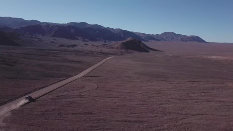 car driving on a dusty road in the atacama desert with an arid landscape in northern chile_follow shot