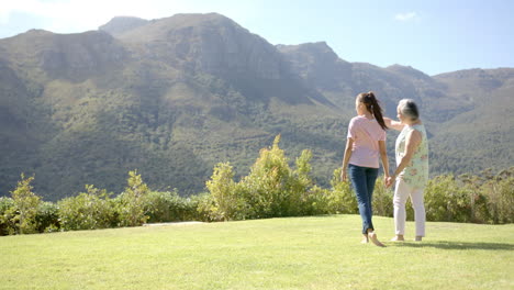 Walking together, young asian woman and elderly asian woman enjoying scenic mountain view, copy spac