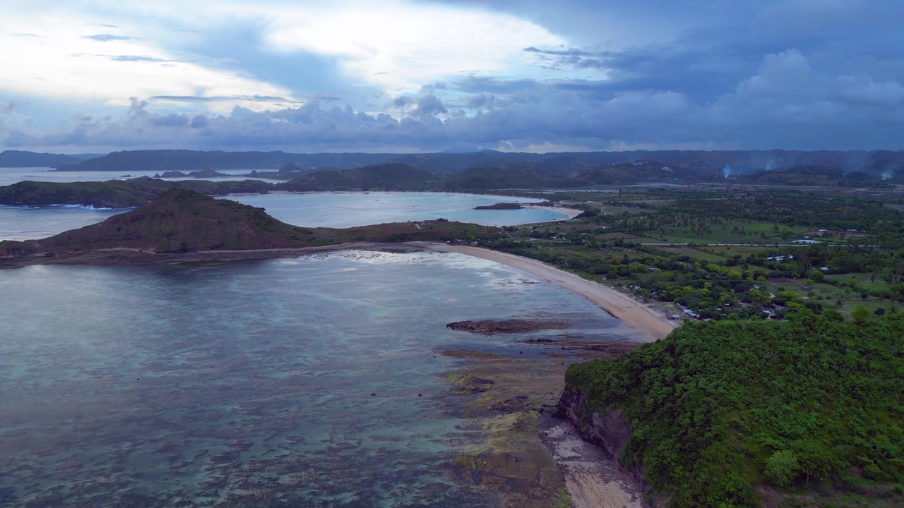 Scogliera verde lussureggiante che si affaccia sull'oceano blu cristallino con piccole onde che si infrangono, suggerendo una destinazione tropicale. Maestosa vista aerea, sorvolo, panorama da drone