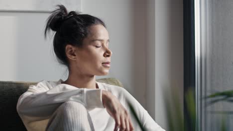 natural woman sitting at home and enjoying the sun on her face.