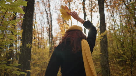 dama de boina amarilla bailando alegremente en un parque de otoño iluminado por el sol, sosteniendo hojas amarillas, los rayos del sol creando un hermoso efecto de luz a su alrededor