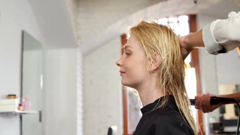 woman getting her hair dried with hair dryer