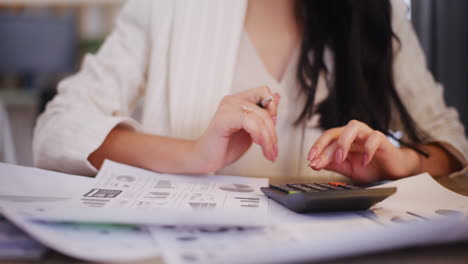 businesswoman uses a calculator while working on the company's financial report