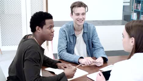 equipo de tres estudiantes universitarios diversos haciendo un proyecto juntos. toma media de compañeros estudiantes sentados en el escritorio y trabajando en grupo