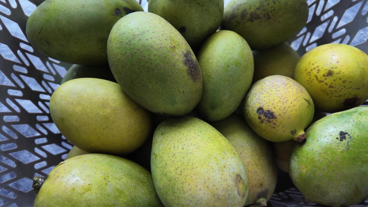 Mango verdi freschi in un cesto di plastica