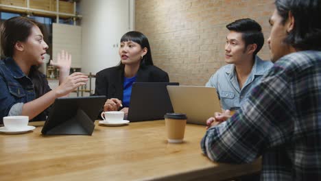 group of happy young asia business coworkers using laptop in team casual meeting startup project discussion at cafe restaurant.
