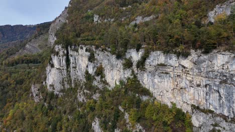 Aerial-view-showing-steep-cliffs-of-swiss-green-mountains-in-Weesen,-Switzerland-during-cloudy-day
