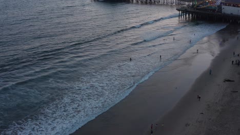 Aerial-shot-flying-over-the-beach-and-tilting-up-to-reveal-the-Santa-Monica-Pier-on-a-beautiful-summer-night-at-twilight