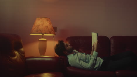 niño acostado en el sofá leyendo un libro