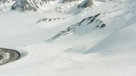 a rotation around a hairpin bend on mountain road with skiiers going past and a cloud inversion below