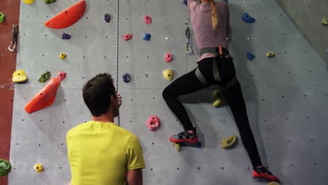 coach assisting a woman in climbing the artificial wall 4k