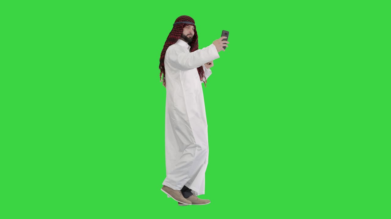 Uomo arabo che cammina e si fa un selfie con il suo telefono su Green Screen, Chroma Key