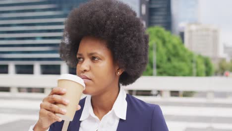 african american businesswoman drinking takeaway coffee in city