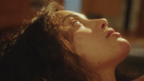 close-up of young contemplative woman resting at home, illuminated by sunlight