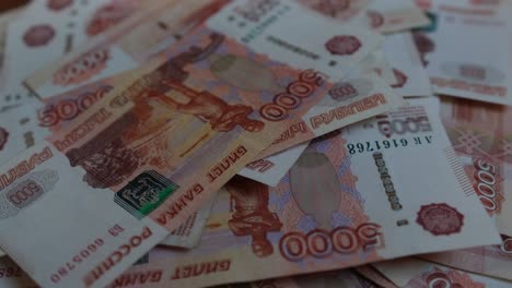 la mano de un hombre cuenta billetes rusos de cinco milésimas, arrojándolos hacia abajo