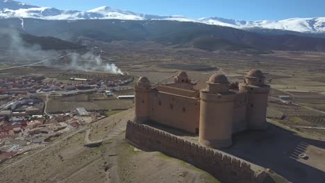 aerial view around the fortress of la calahorra in granada with snowed sierra nevada behind