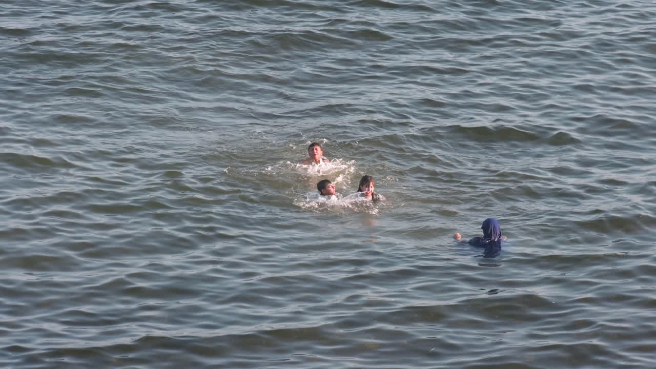 Campello Beach in Alicante, Spain, offers a peaceful Mediterranean setting where a family of swimmers has a great time.