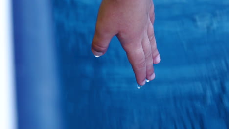 Slow-motion-shot-of-child's-hand-touching-the-moving-water-as-a-small-fishing-boat-travels-on-Atlantic-Ocean-in-Portugal