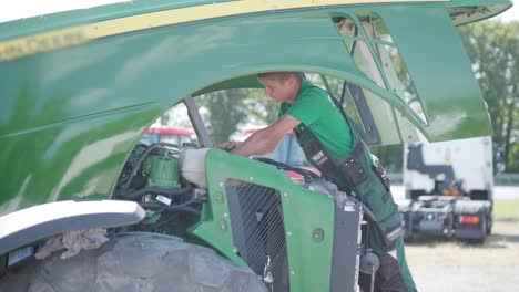 farmer mechanic repairing tractor. open tractor hood, engine. repair agricultural technology