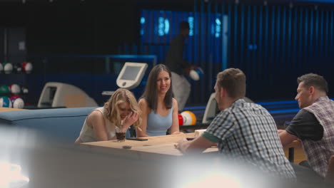 a joyful black man runs up to friends giving five different ethnic groups of people sitting at a table in a bowling. to celebrate and congratulate on the victory and the scored streak. victory dance
