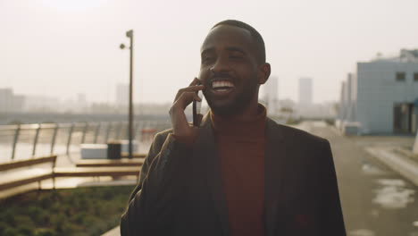 young black businessman walking on street and speaking on phone