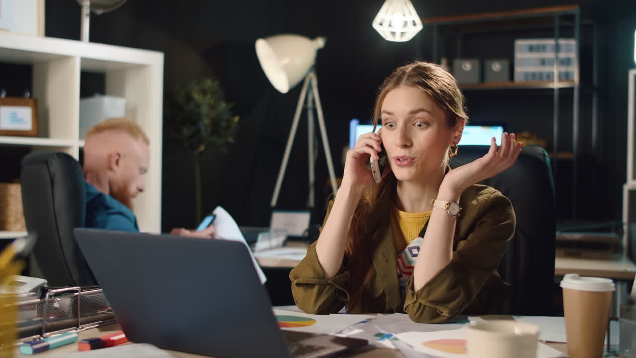 Smuk kvinde taler i telefon indendørs. Glad forretningskvinde flirter på kontoret.