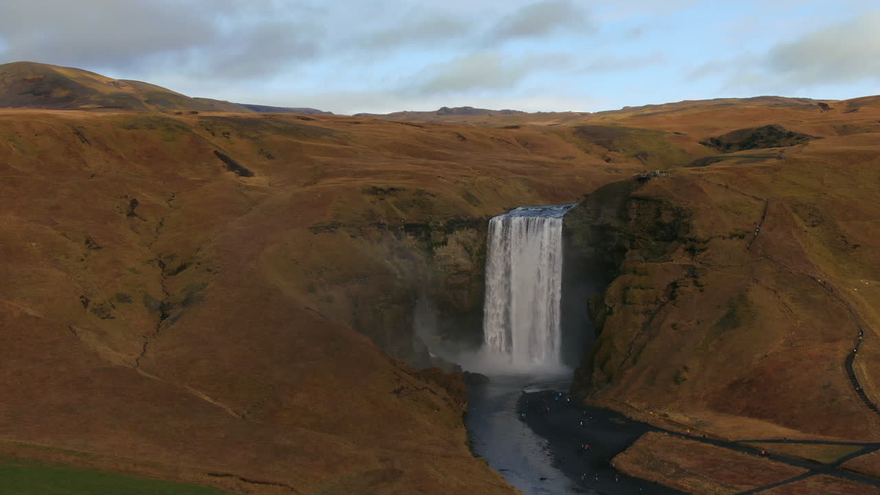avión no tripulado cinematográfico cascada de skogafoss islandia pan al movimiento derecho con pájaros, arco iris y tarde de la tarde nubes de luz solar