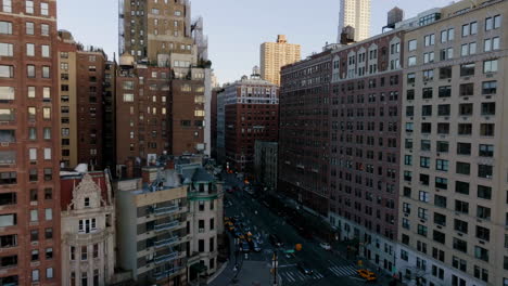 Aerial-view-of-birds-flying-in-middle-of-buildings-on-the-Upper-West-Side-of-Manhattan,-sunrise-in-NY,-USA---reverse,-drone-shot