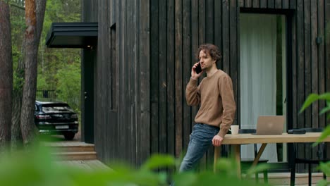 man talking on phone outdoors at cabin