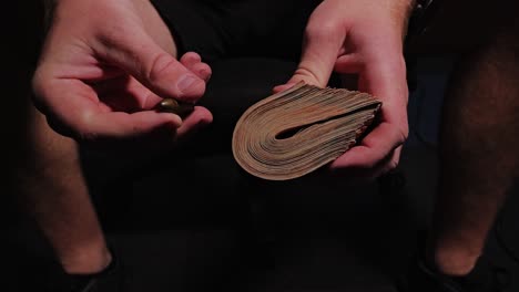 symbolic slow motion capture of man holding currency and bullet in moody light