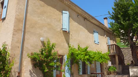 quaint village house with bright blue shutters in glandage, southern france
