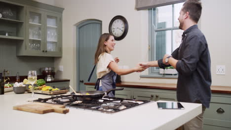 una pareja bailando en la cocina.