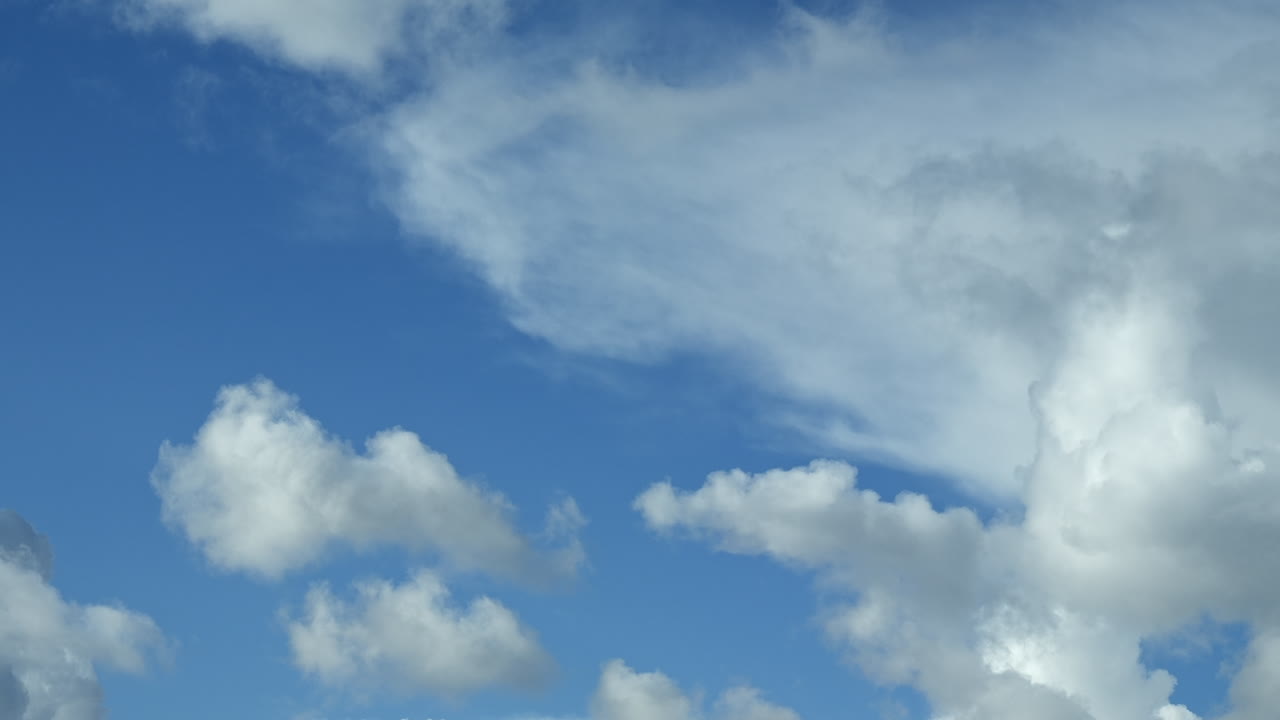 Time lapse of white clouds moving with blue patches of sky