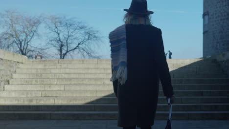 woman walking up stone steps casting shadow in sunny day