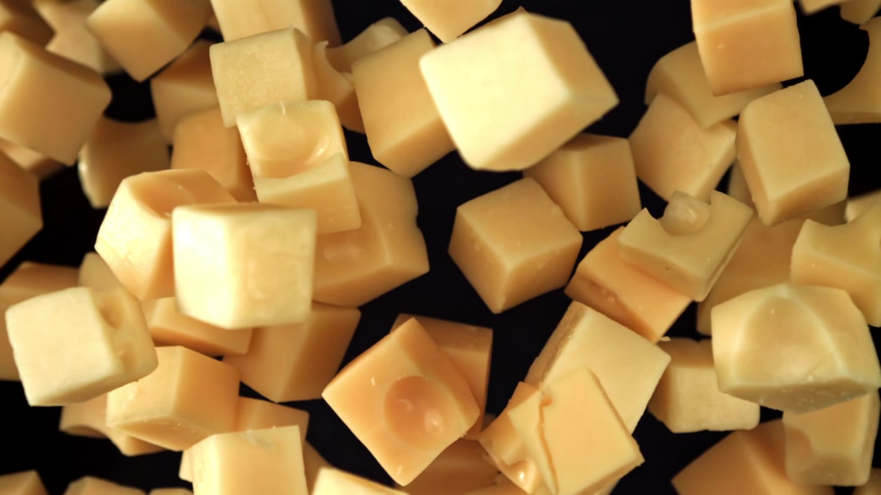 Cubes de fromage jaune coupés en dés tombant au ralenti extrême