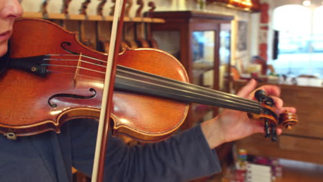 customer tuning violin in music store before playing