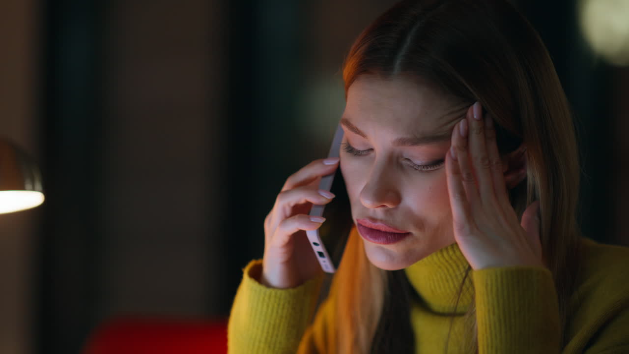 Fatigued employee talking cellphone sitting night workplace closeup. Tired woman