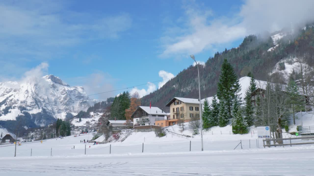 una magnífica cresta montañosa cubierta de nieve se ve en una vista panorámica junto con chalets de montaña y casas de ciudadanos locales, engelberg, suiza