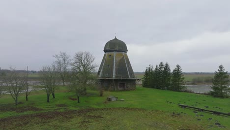 Beautiful-aerial-establishing-view-of-old-wooden-windmill-in-the-middle-of-the-field,-Prenclavu-windmill-,-overcast-winter-day,-wide-ascending-drone-shot-moving-forward