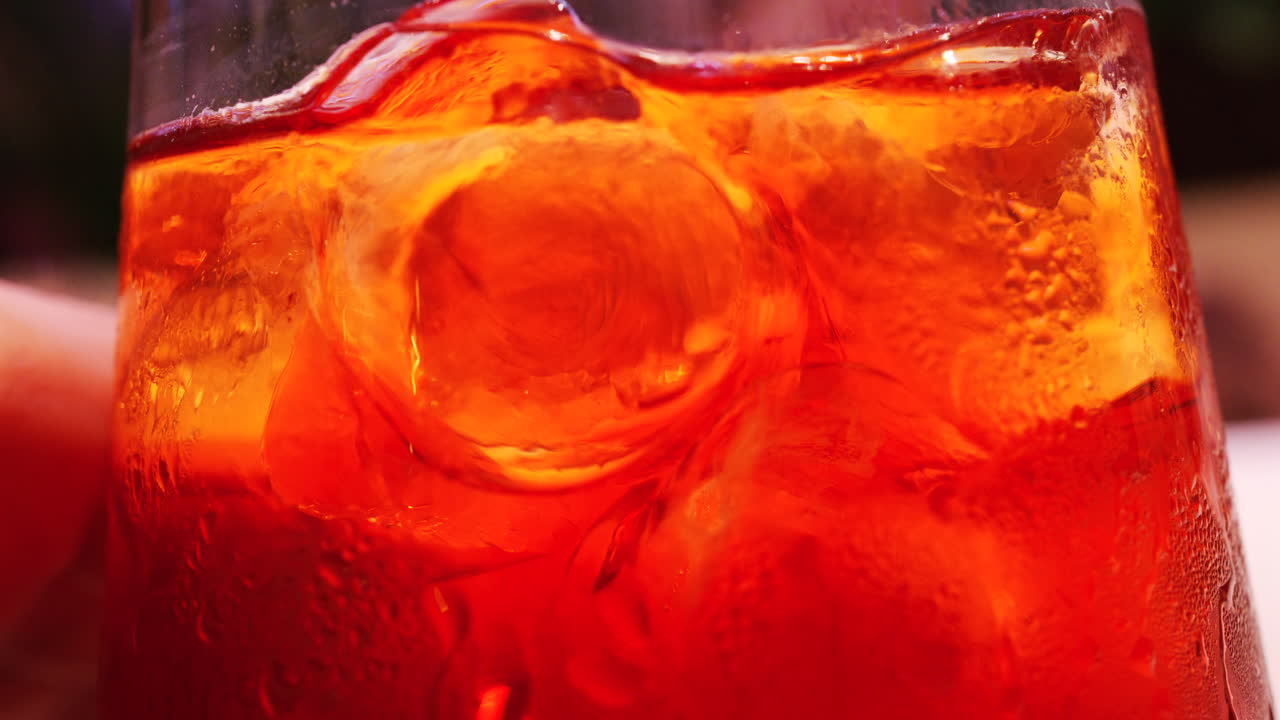 Primo piano macro dettagliato di un cocktail rinfrescante con cubetti di ghiaccio e goccioline d'acqua sulla superficie del bicchiere