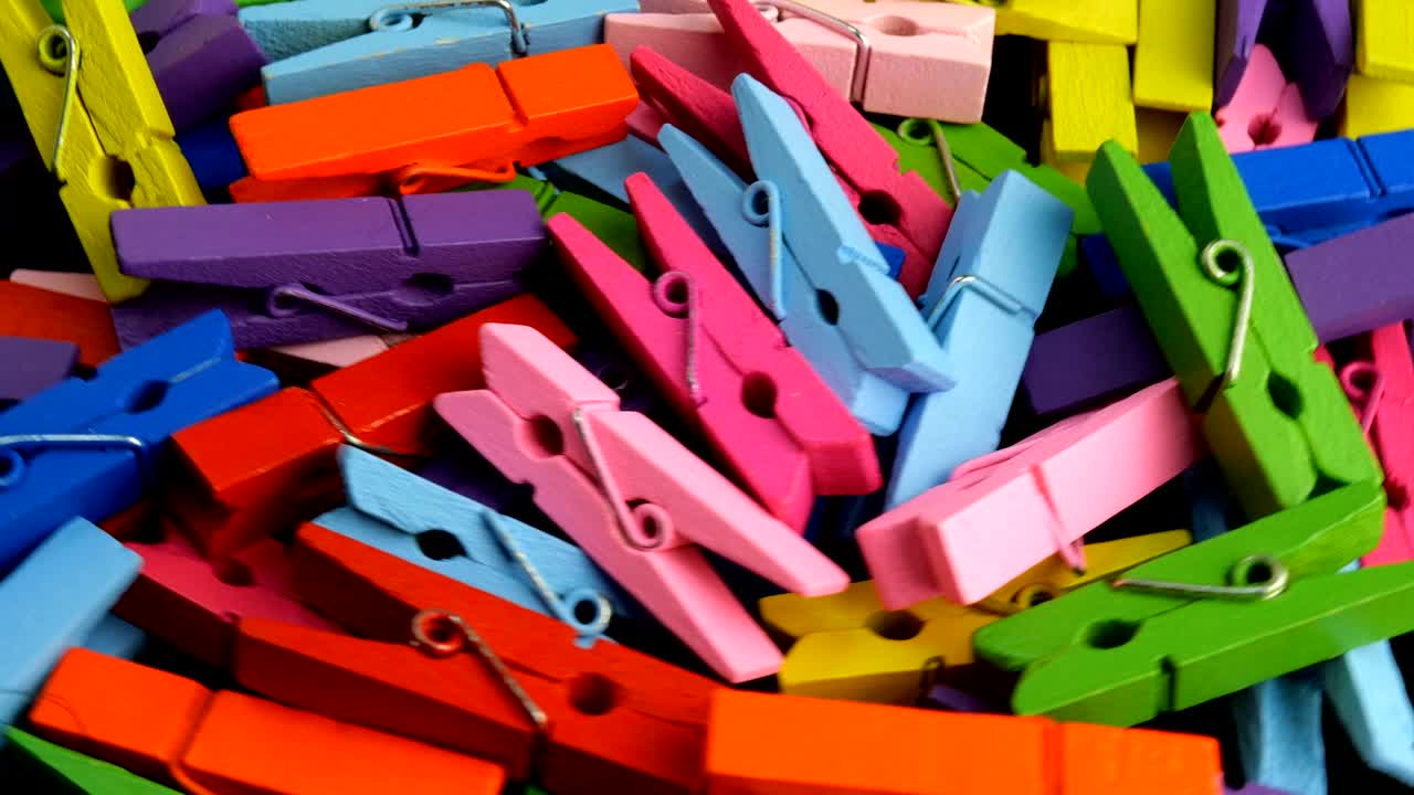 muchas pinzas de ropa de madera de varios colores en montón giran en círculo.