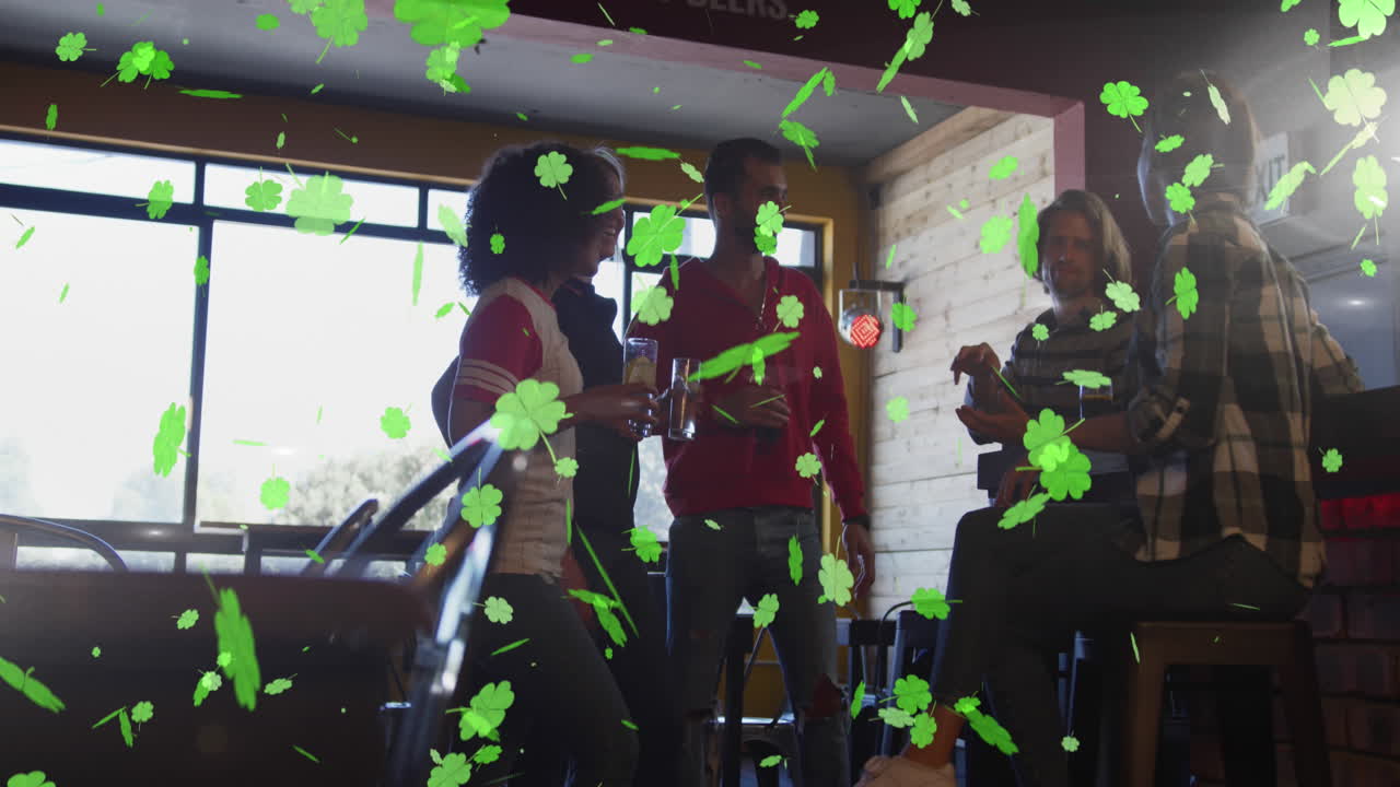 Animation of st patrick's day green shamrock falling over diverse friends having fun at party